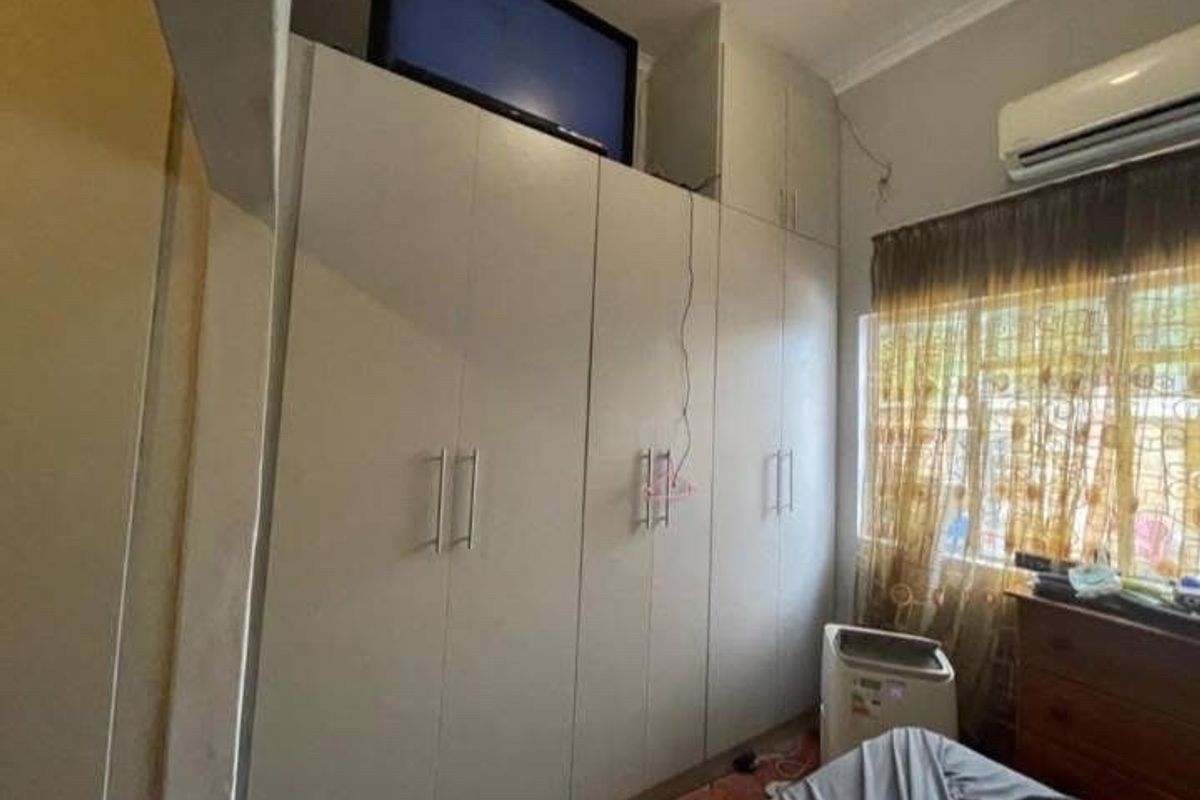 Bedroom featuring extensive floor-to-ceiling built-in cabinetry with modern handles and a wall-mounted air conditioning unit.