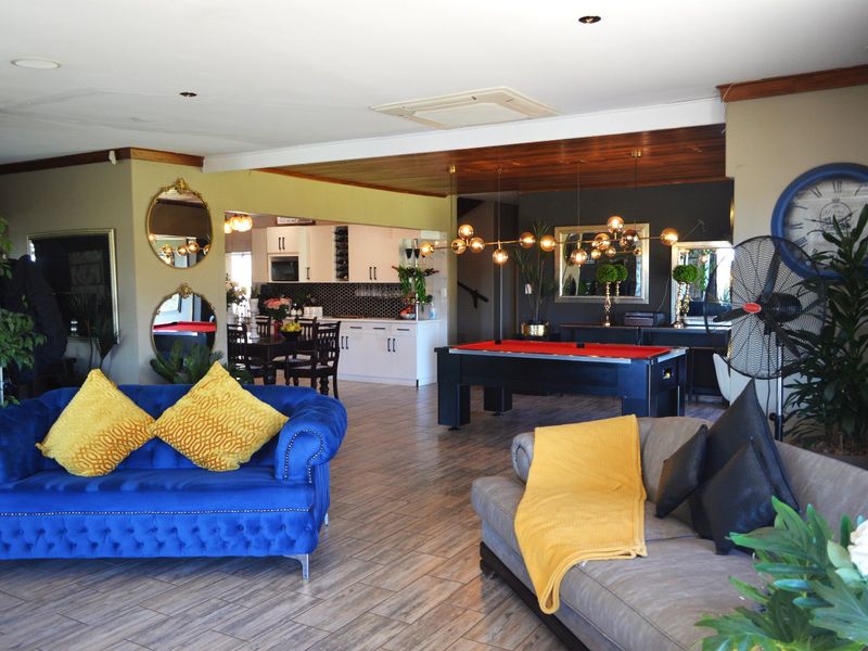 Spacious open-plan living area featuring tiled flooring, timber ceiling accents, and a modern kitchen with built-in appliances and a tiled backsplash.