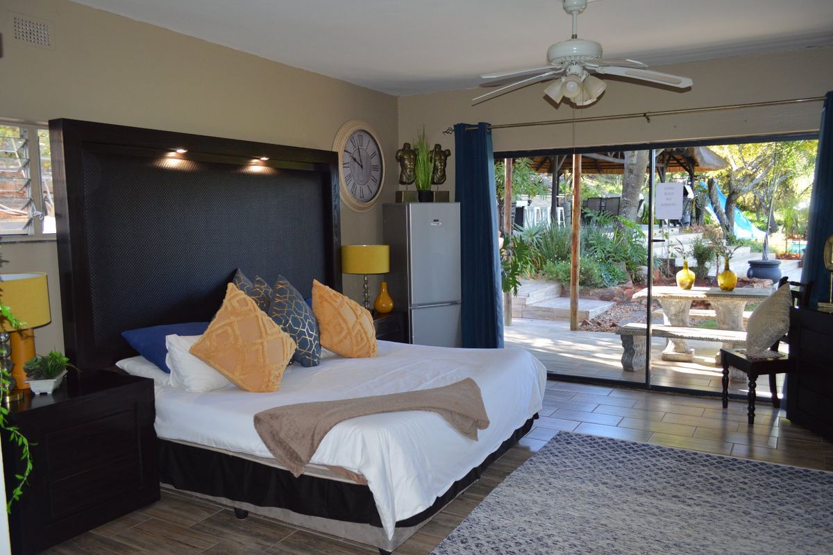 Spacious bedroom featuring tiled flooring, a ceiling fan, and large sliding glass doors providing direct access to an outdoor patio area.