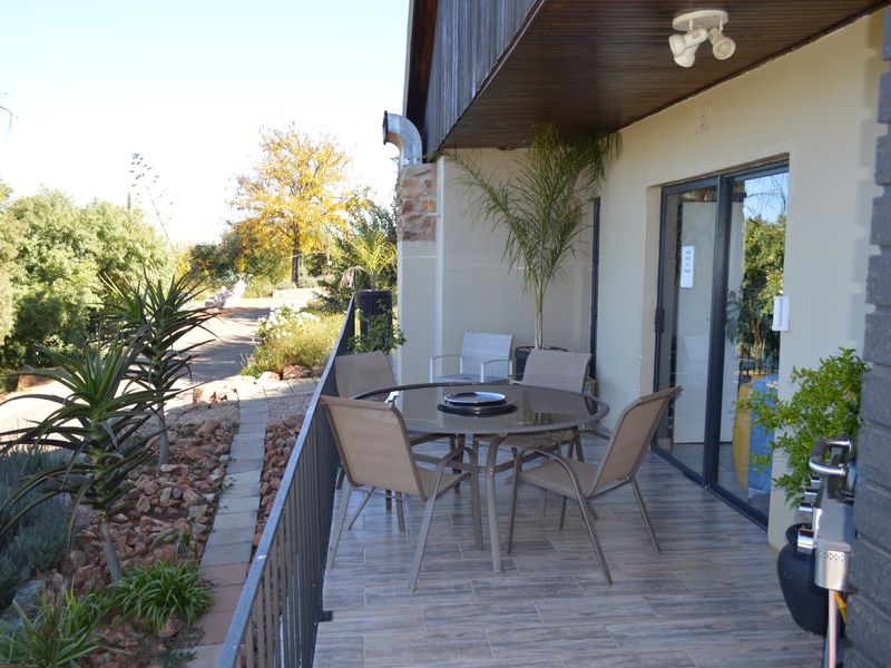 A covered outdoor patio featuring tiled flooring, timber ceiling cladding, and a metal safety railing, providing direct access to the interior via sliding glass doors.