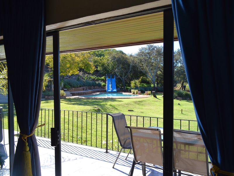 A covered patio area featuring sliding glass doors that open onto a landscaped garden with a swimming pool and slide.