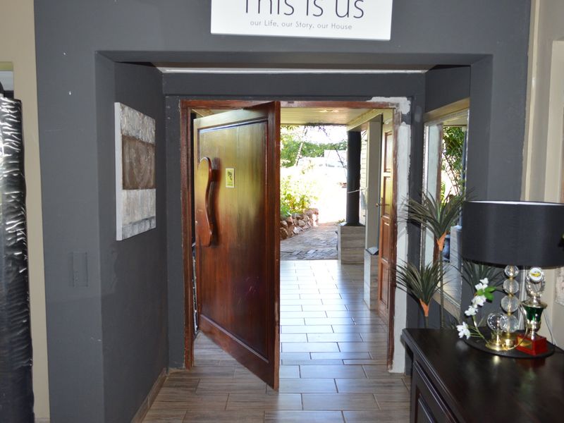 Entrance area featuring a solid wood door and tiled flooring, leading to an outdoor patio space. The door frame requires finishing touches.