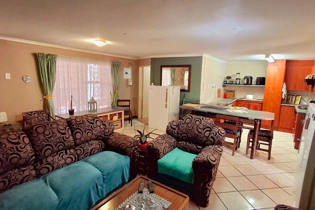 Open-plan living and kitchen area featuring tiled flooring, built-in cabinetry, and a functional layout connecting the lounge and dining space.