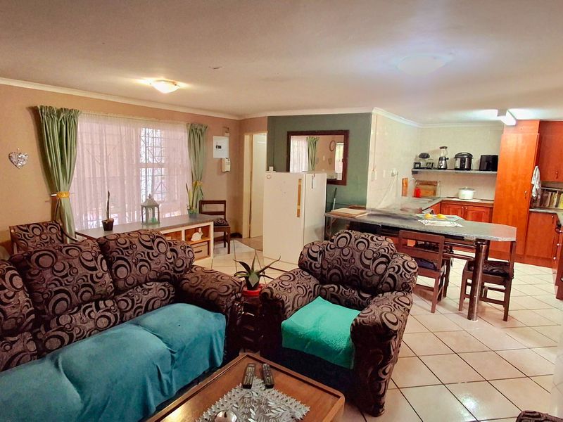 Open-plan living and kitchen area featuring tiled flooring, built-in cabinetry, and a functional layout connecting the lounge and dining space.