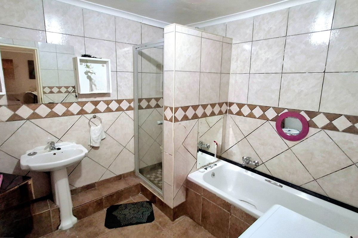 A functional bathroom featuring a pedestal basin, a separate shower enclosure, and a bathtub with tiled wall finishes.