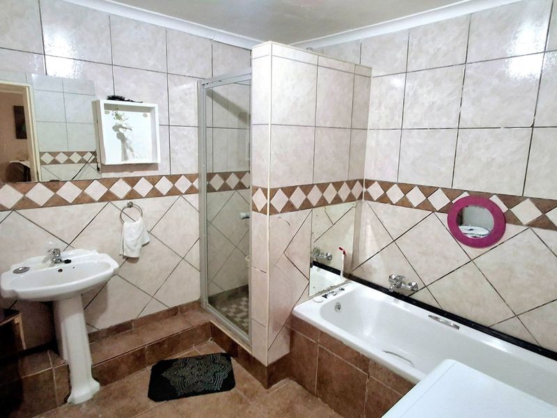 A functional bathroom featuring a pedestal basin, a separate shower enclosure, and a bathtub with tiled wall finishes.