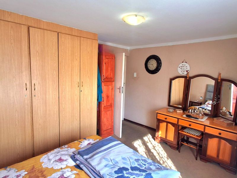A bedroom featuring built-in wooden cupboards and neutral wall finishes, offering a functional space with potential for modern updates.