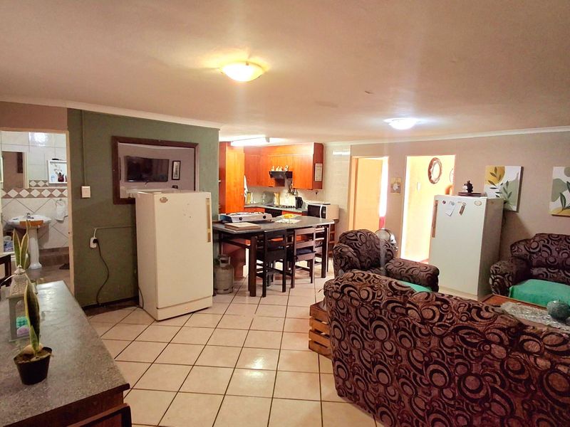 Spacious open-plan living and kitchen area featuring tiled flooring and functional built-in cabinetry, offering a versatile layout for dining and relaxation.