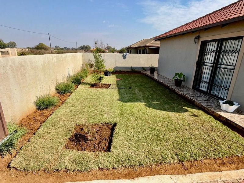 A private rear garden featuring a small lawn, tiled patio area, and perimeter walling, providing a functional outdoor space for the townhouse.
