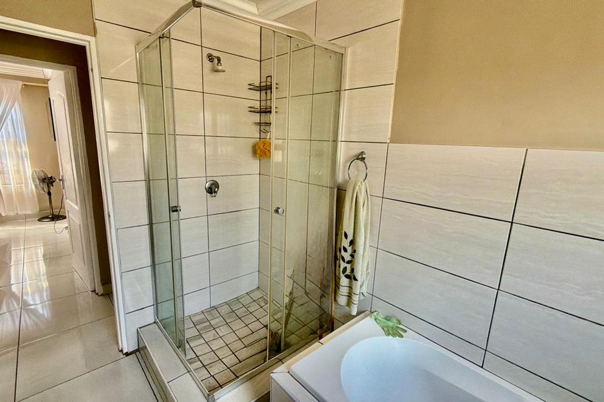 A functional bathroom featuring a glass-enclosed shower, tiled walls, and a built-in bathtub, providing a clean and practical layout.