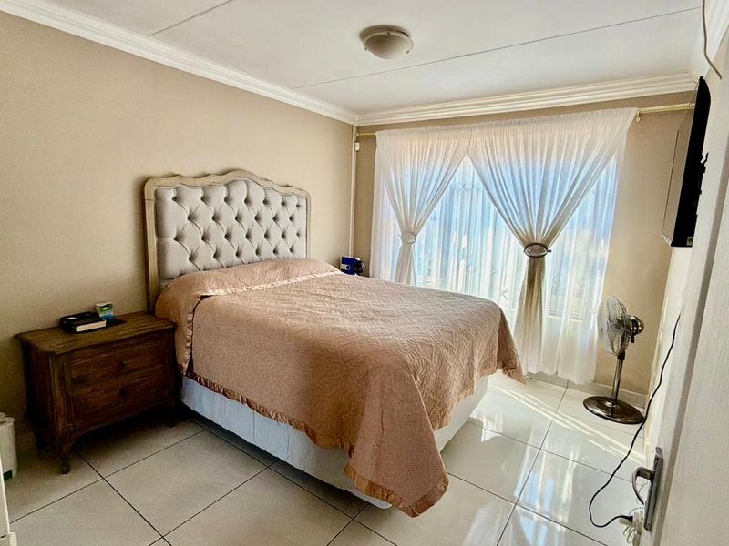 A bedroom featuring tiled flooring and neutral wall tones, offering a functional space with natural light through the window.