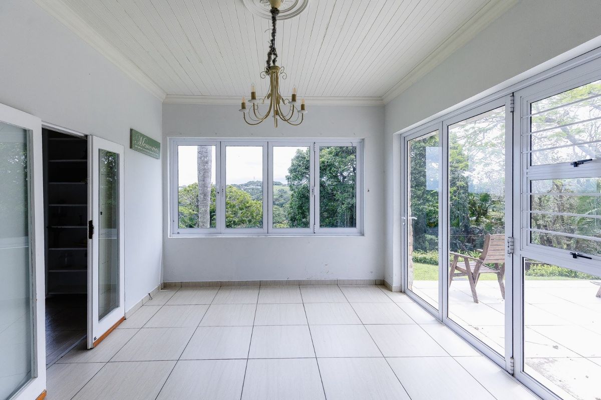 Bright and airy living space featuring tiled flooring, beadboard ceiling with decorative rose, and large sliding glass doors opening to the garden.