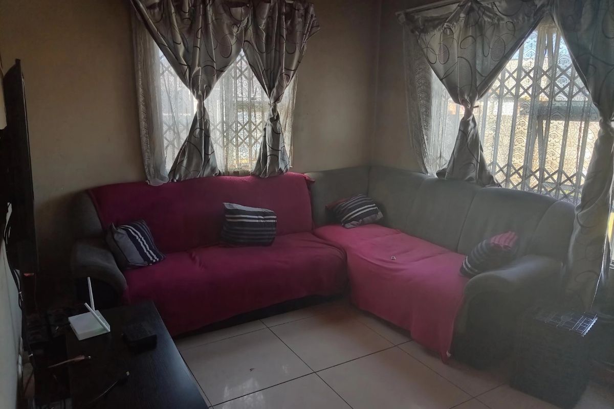 A living room featuring tiled flooring and security gates on the windows, requiring cosmetic updates to the wall finishes.