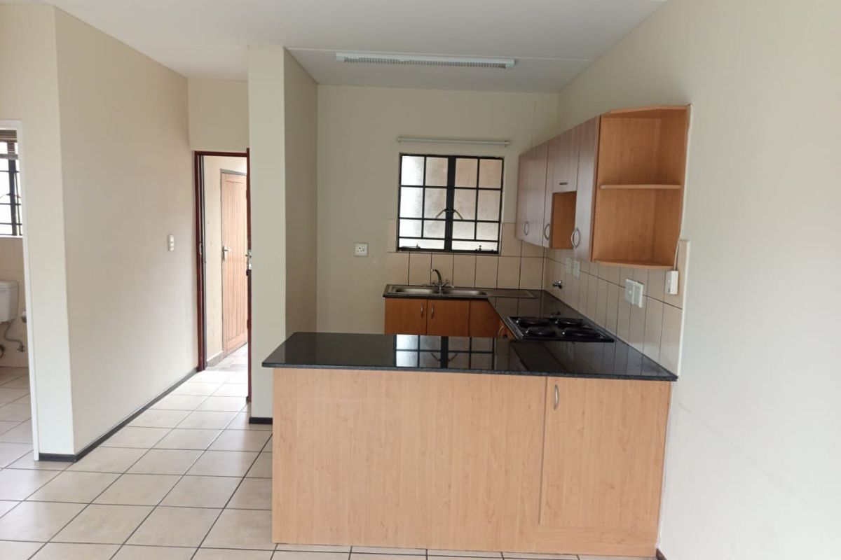 A functional kitchen featuring built-in wooden cabinetry, granite countertops, a built-in hob, and tiled flooring, offering a clean and practical workspace.