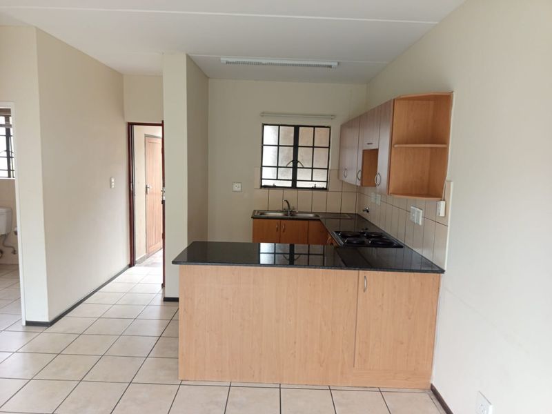 A functional kitchen featuring built-in wooden cabinetry, granite countertops, a built-in hob, and tiled flooring, offering a clean and practical workspace.