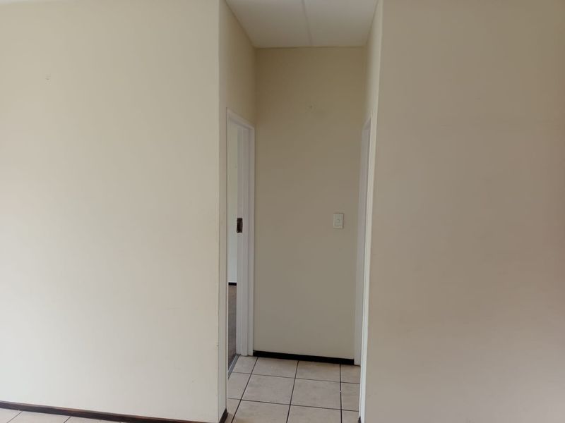A simple, empty hallway with neutral walls and tiled flooring, providing access to adjacent rooms.