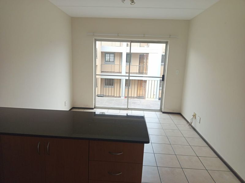 An open-plan living area featuring a kitchen island with granite countertops, tiled flooring, and a sliding glass door leading to a balcony.