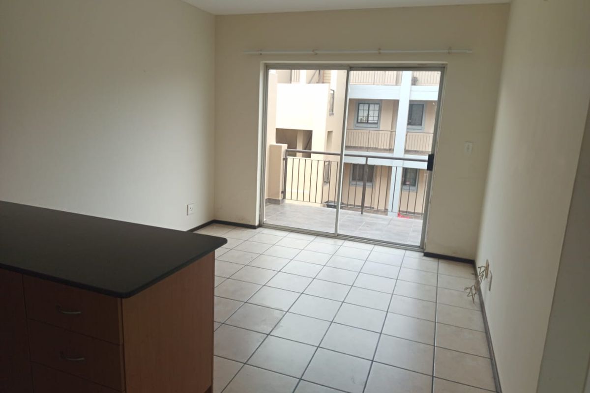 An empty living area featuring tiled flooring and a sliding glass door providing access to a balcony.