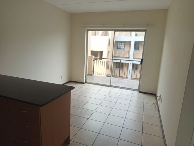 An empty living area featuring tiled flooring and a sliding glass door providing access to a balcony.