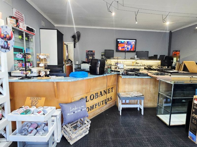 Commercial retail space featuring a built-in service counter, track lighting, and durable rubber flooring, currently utilized as a computer store.