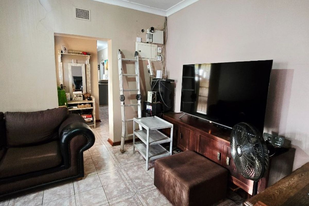Living room featuring tiled flooring, a ceiling fan, and coved cornicing, with visible wall plaster cracking near the ceiling.