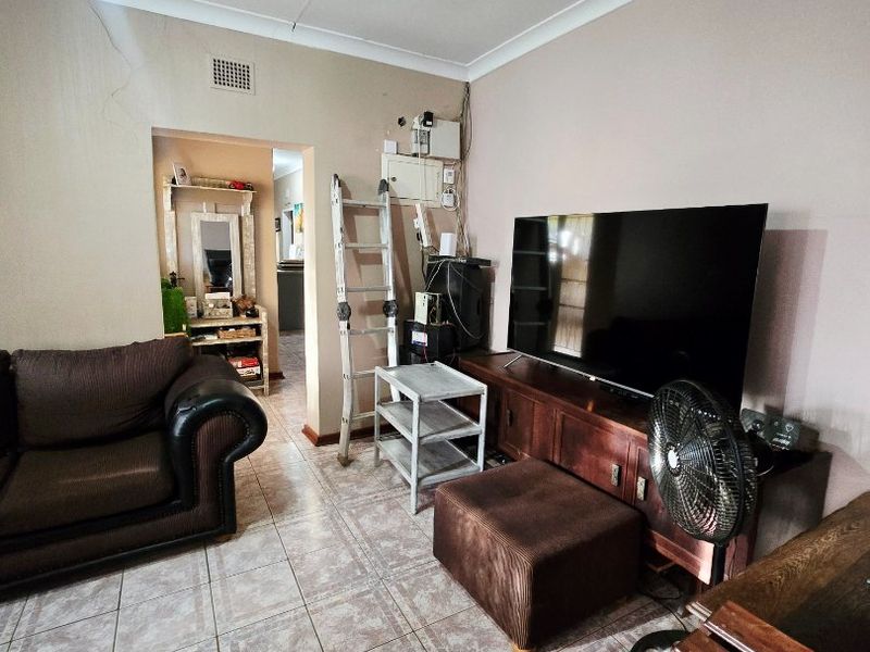 Living room featuring tiled flooring, a ceiling fan, and coved cornicing, with visible wall plaster cracking near the ceiling.