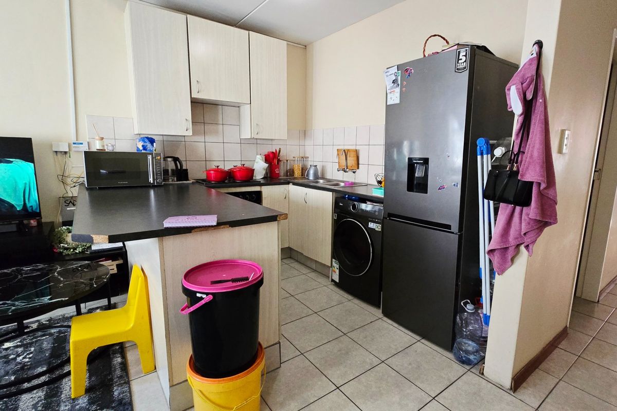Compact kitchen featuring laminate cabinetry, tiled backsplash, ceramic flooring, and a built-in sink with an integrated washing machine space.