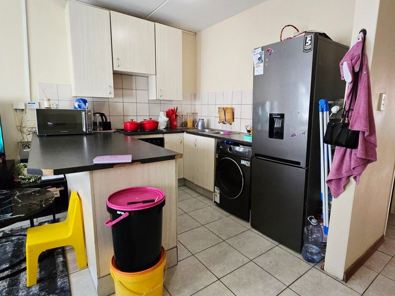 Compact kitchen featuring laminate cabinetry, tiled backsplash, ceramic flooring, and a built-in sink with an integrated washing machine space.