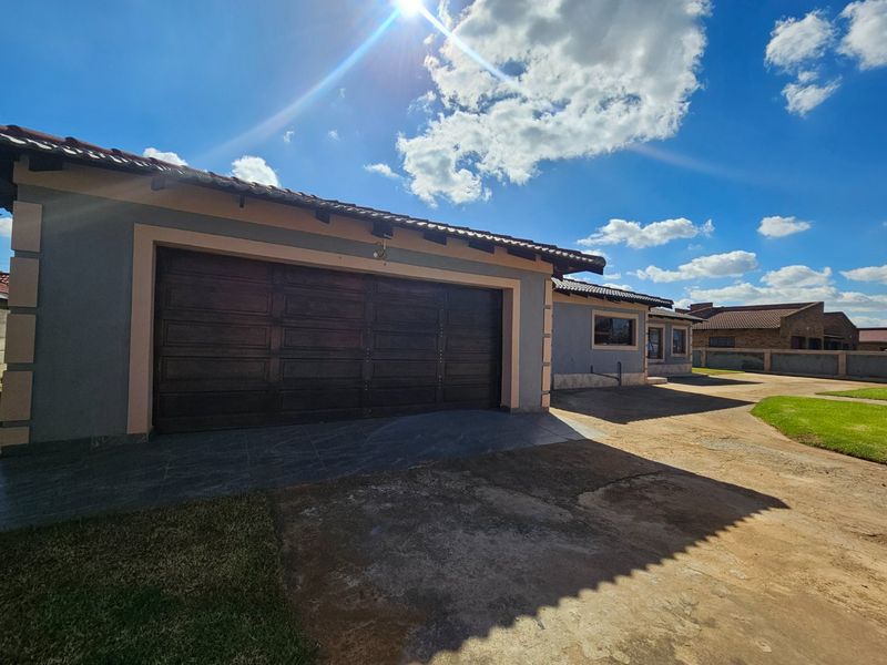 Front exterior view of the property featuring a double garage, tiled roof, and concrete driveway area.