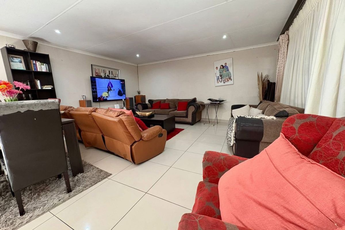 Spacious living room featuring large format floor tiles and recessed ceiling lighting, providing a functional and open layout for family relaxation.