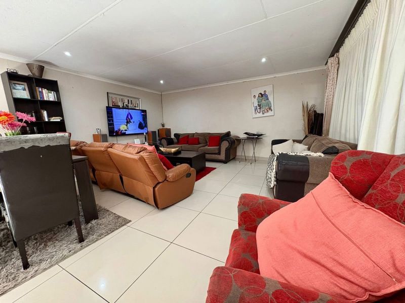 Spacious living room featuring large format floor tiles and recessed ceiling lighting, providing a functional and open layout for family relaxation.