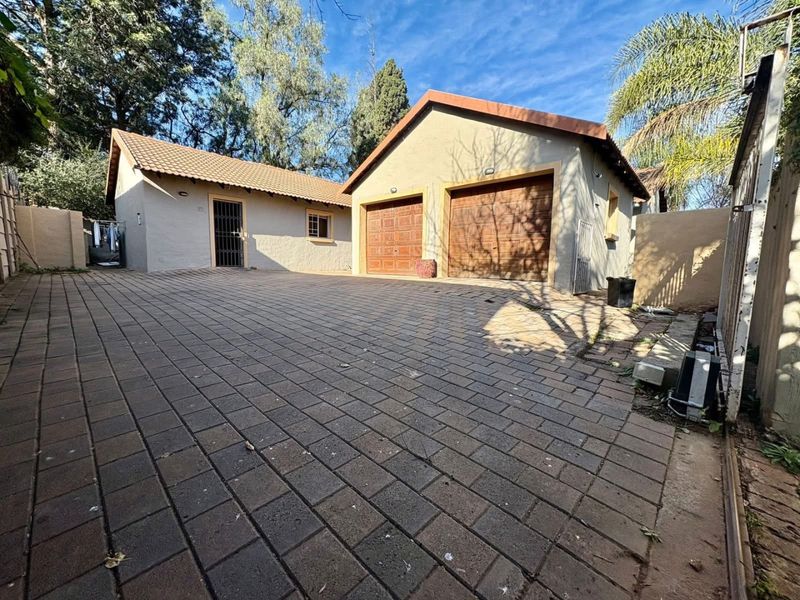 Front exterior view of the property featuring a double garage, paved driveway, and secure entrance.