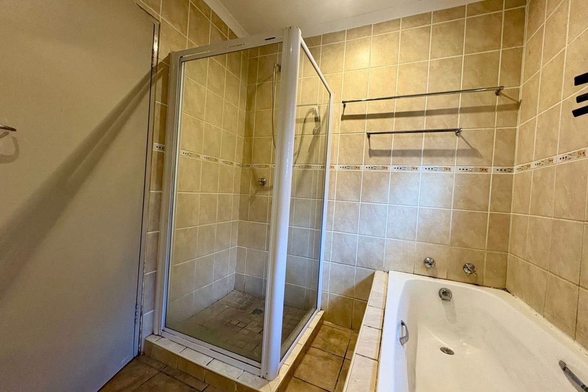 A functional bathroom featuring a separate shower enclosure, a built-in bathtub, and neutral ceramic wall and floor tiling.