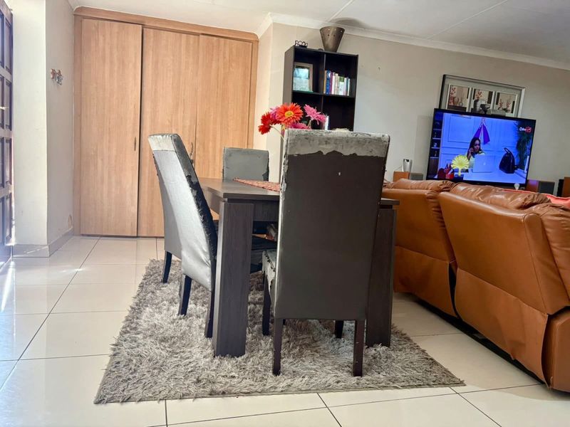 Open plan living and dining area featuring neutral tiled flooring and built-in wooden cabinetry.