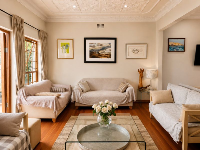 A well-maintained living room featuring polished hardwood floors, an ornate coffered ceiling, and natural light through timber-framed windows and doors.