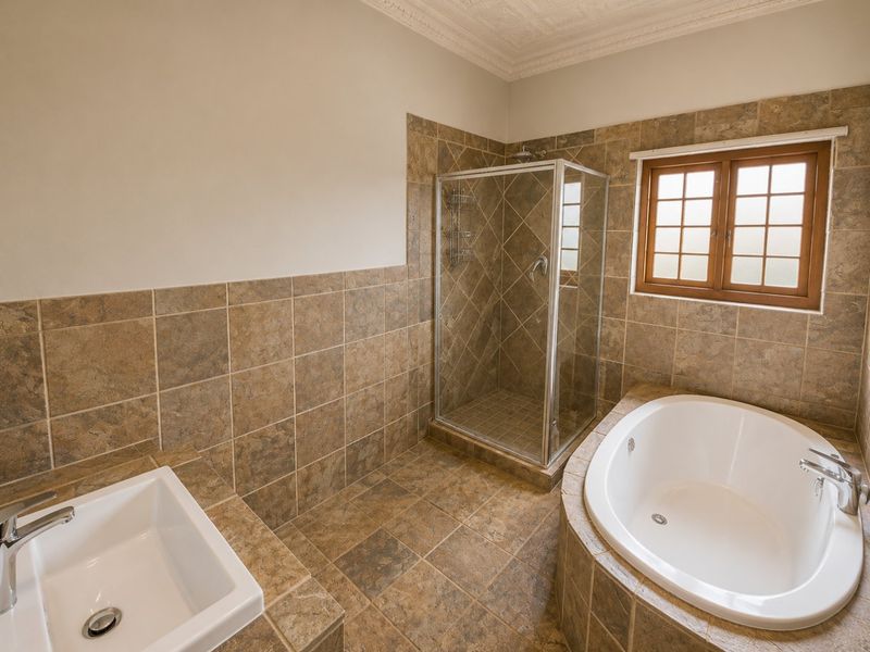 A well-maintained bathroom featuring a built-in bathtub, a separate glass-enclosed shower, and a tiled vanity with a basin.