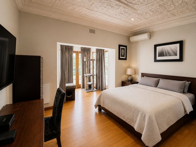 Spacious bedroom featuring laminate flooring, an ornate pressed metal ceiling, and direct access to the outdoors through double glass doors.