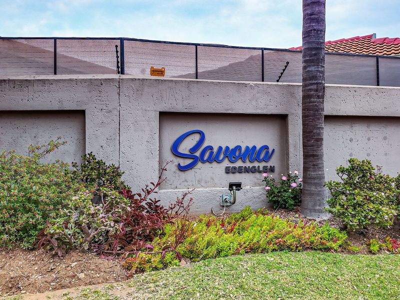 Front entrance view of the Savona Edenglen complex, featuring a concrete boundary wall with integrated signage and established garden landscaping.