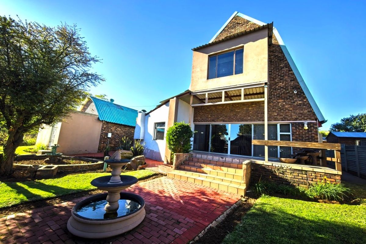 Rear view of a multi-level brick house featuring a paved patio, stone fountain, and sliding glass doors leading to the interior living space.