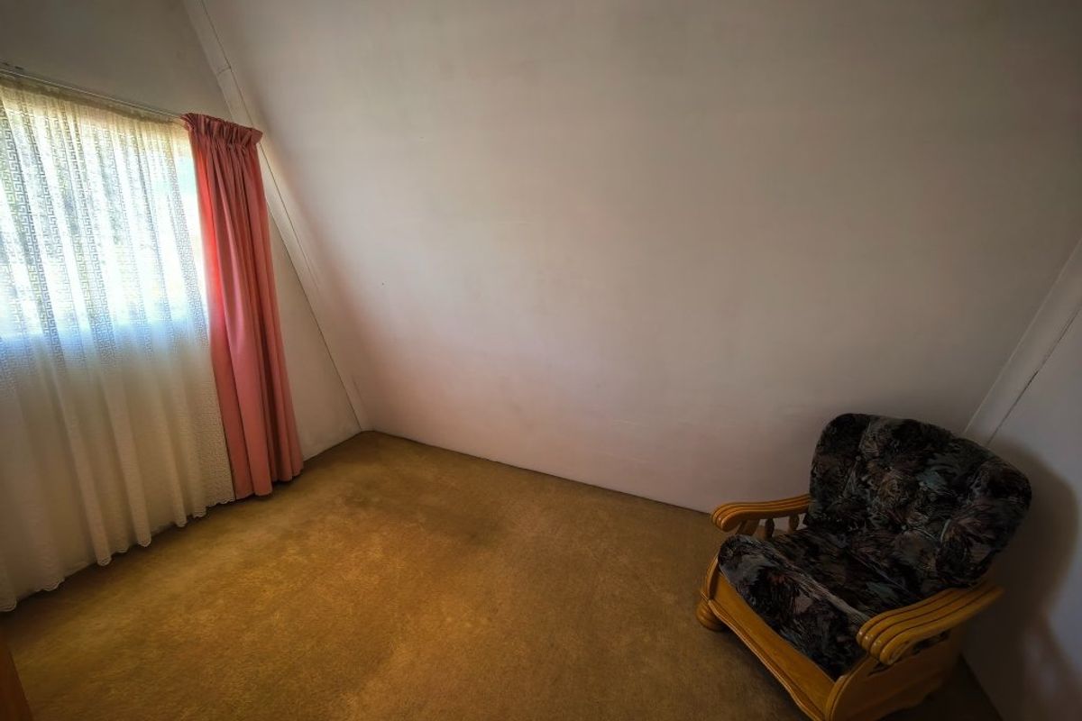 A bedroom featuring a sloped ceiling and carpeted flooring, requiring cosmetic updates to improve its overall condition and appeal.
