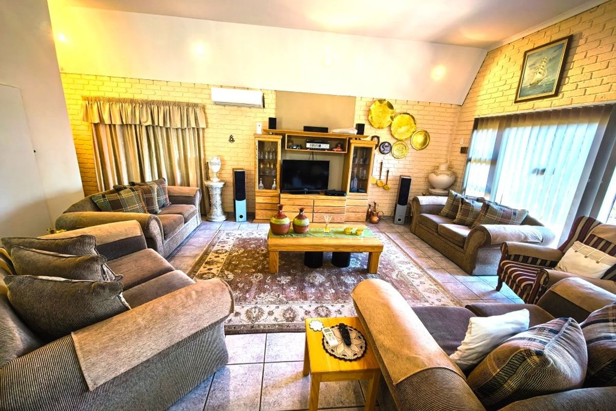 Spacious living room featuring exposed brick walls, vaulted ceilings, and tiled flooring, offering a comfortable and well-lit area for relaxation.