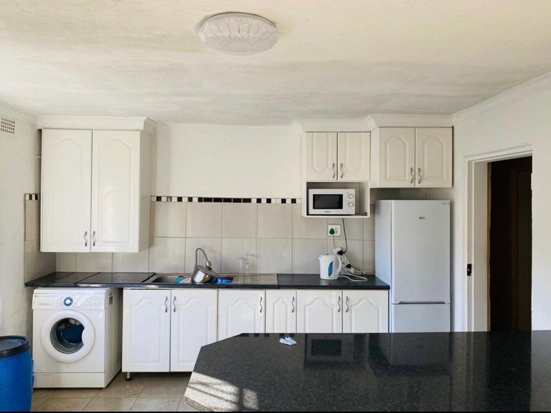 A functional kitchen featuring white cabinetry, dark countertops, a tiled backsplash, and integrated appliance space, offering a practical layout for daily use.