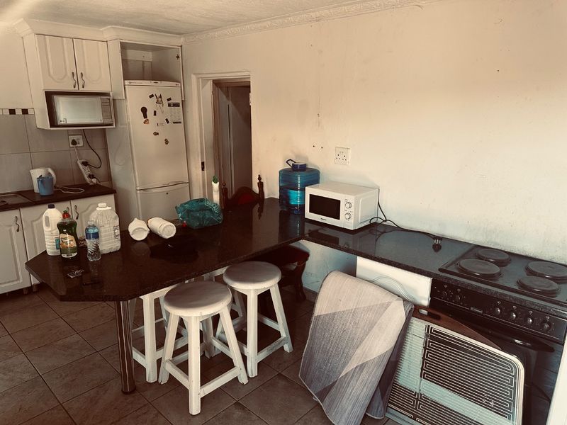 A functional kitchen featuring granite countertops, built-in cabinetry, and an electric stove, requiring cosmetic updates to improve its overall condition.