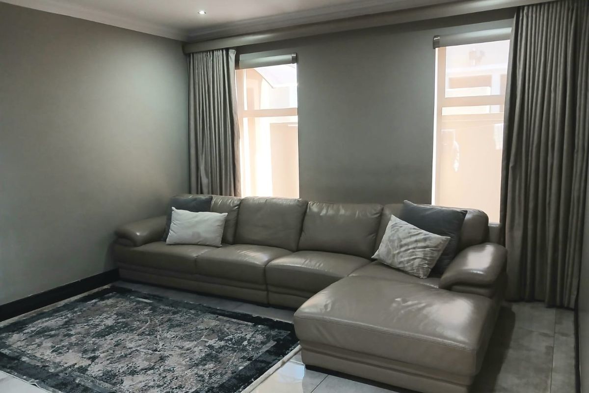 A well-maintained living room featuring neutral wall tones, tiled flooring, and recessed downlighting, creating a comfortable and modern living space.
