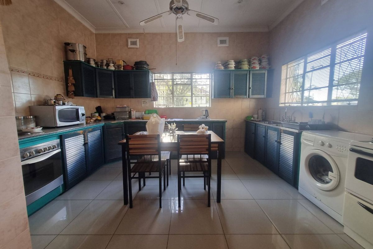 Spacious kitchen featuring tiled walls and floors, built-in cabinetry, integrated oven, and dedicated laundry plumbing connections.