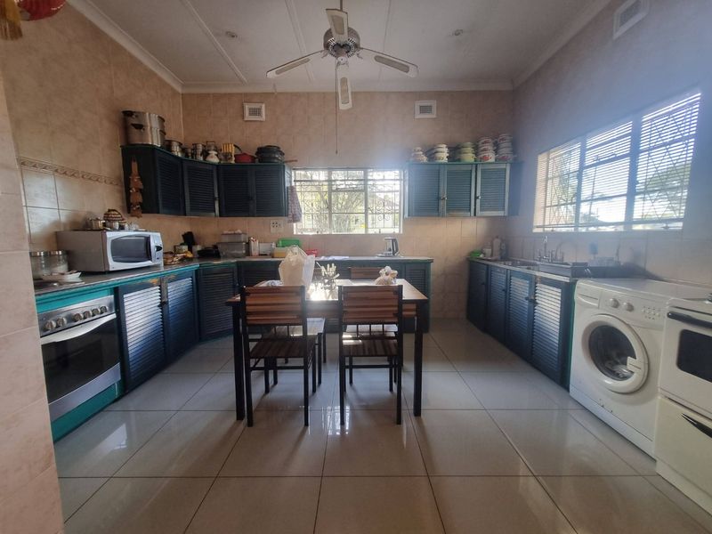 Spacious kitchen featuring tiled walls and floors, built-in cabinetry, integrated oven, and dedicated laundry plumbing connections.