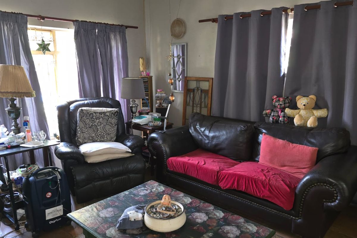 A living room featuring large windows with curtain rods and neutral wall finishes.