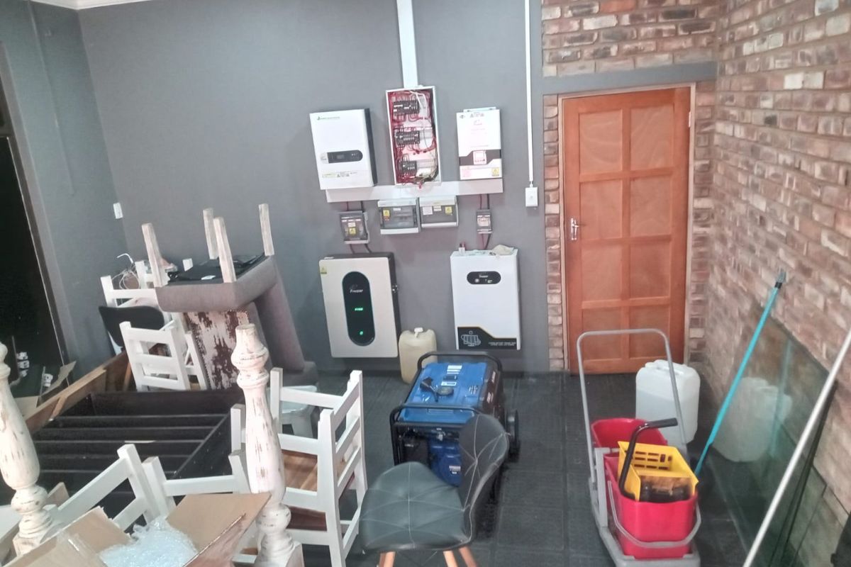 Utility space featuring a solar power installation, battery storage system, and electrical distribution board, with exposed brickwork and tiled flooring.