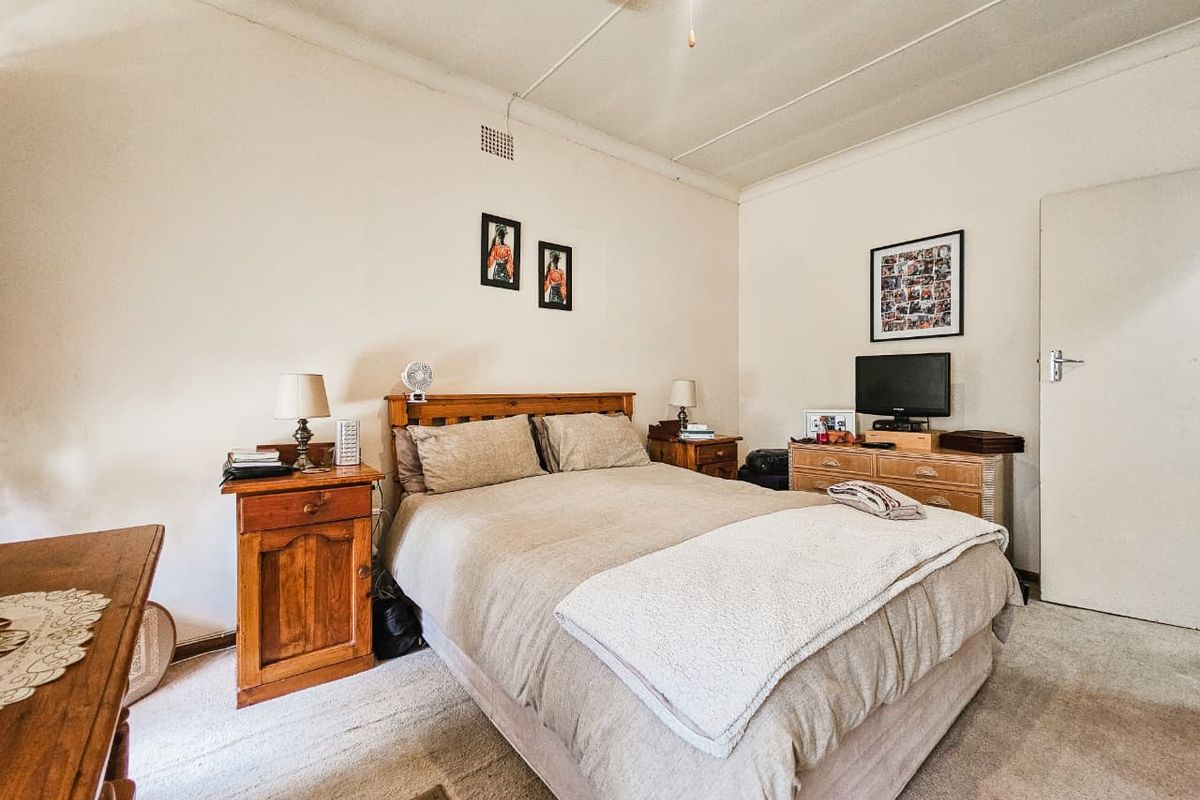 A functional bedroom featuring neutral wall finishes, carpeted flooring, and a ceiling fan, offering a comfortable and well-proportioned living space.