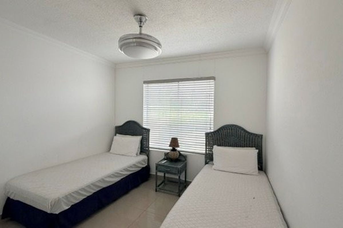 A functional bedroom featuring tiled flooring, a ceiling fan, and window blinds, providing a neutral space ready for personalization.